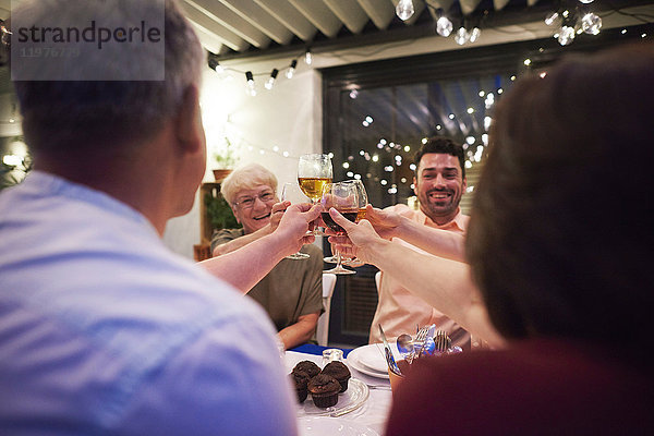 Gruppe von Personen  die am Tisch sitzen  Weingläser halten und einen Toast aussprechen