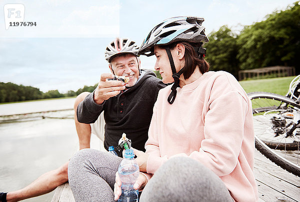Ein erwachsenes Paar entspannt sich auf dem Steg  genießt einen Imbiss  Fahrräder hinter sich