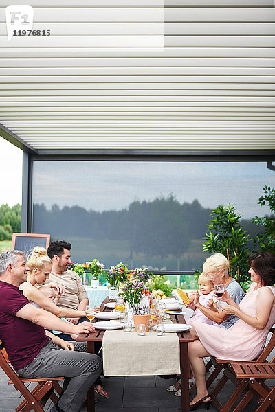 Drei-Generationen-Familie mit Familienessen auf der Terrasse
