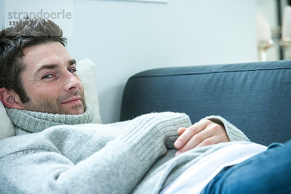 Porträt eines mittelgroßen Mannes  der im Liegen auf dem Sofa zur Seite schaut