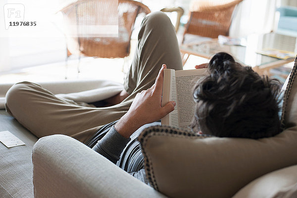 Mittelgroßer Mann entspannt auf Sofa  Buch lesen  Rückansicht