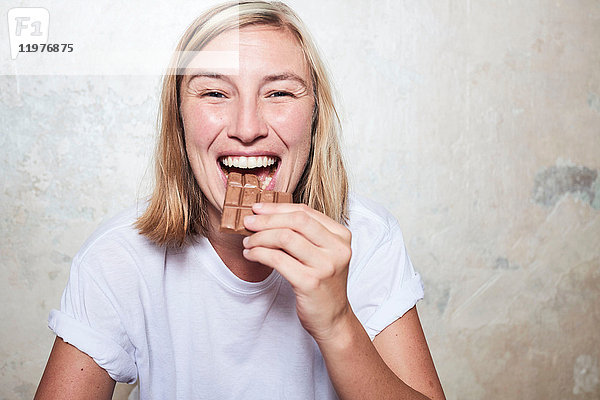 Porträt einer Frau  die eine Tafel Schokolade isst