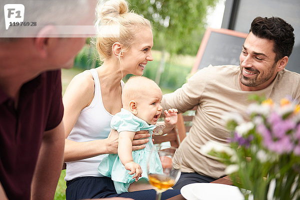 Ehepaar mit kleiner Tochter beim Familienessen auf der Terrasse