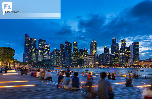 Touristen  die in der Abenddämmerung die Skyline der Stadt vom Wasser aus betrachten  Singapur  Südostasien