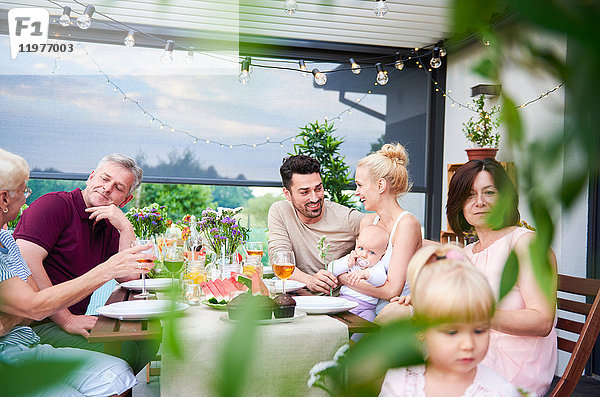 Drei-Generationen-Familie beim Mittagessen auf der Terrasse