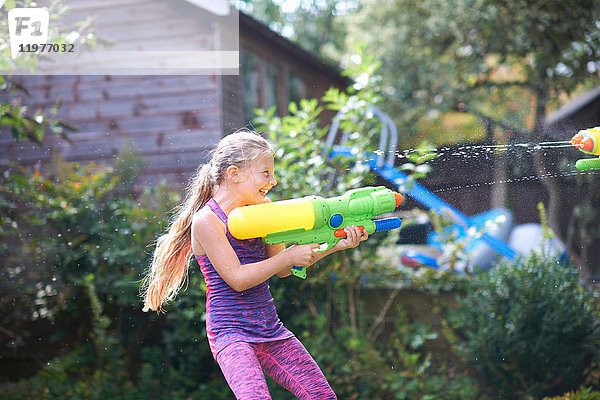 Wasserpistole spritzendes Mädchen im Garten