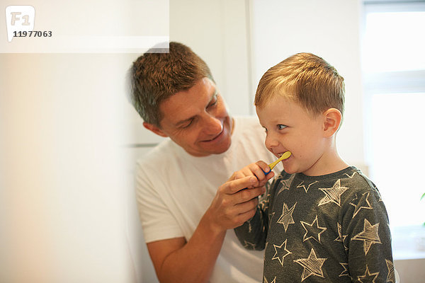 Reifer Mann zeigt Sohn beim Zähneputzen im Badezimmer