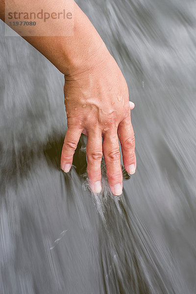 Frau  die die Hand im Wasser zieht