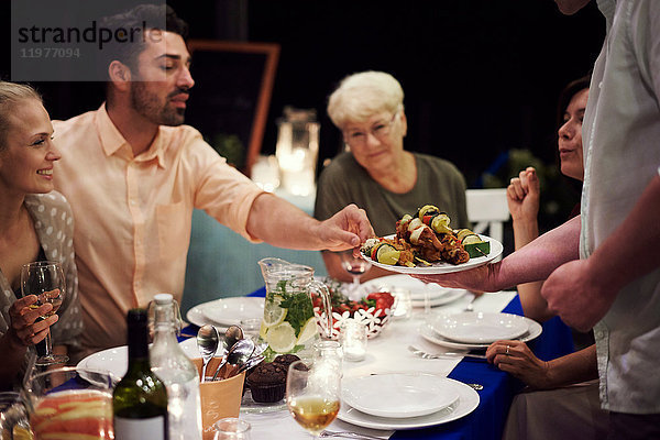 Gruppe von Personen  die am Tisch sitzen und eine Mahlzeit genießen