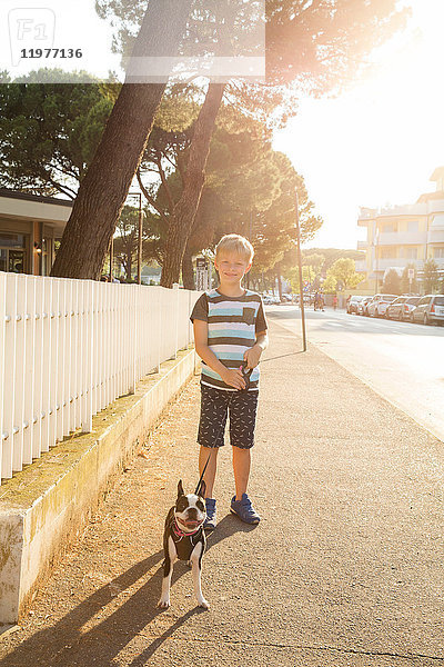 Porträt eines Jungen mit Hund auf der Straße  der lächelnd in die Kamera schaut