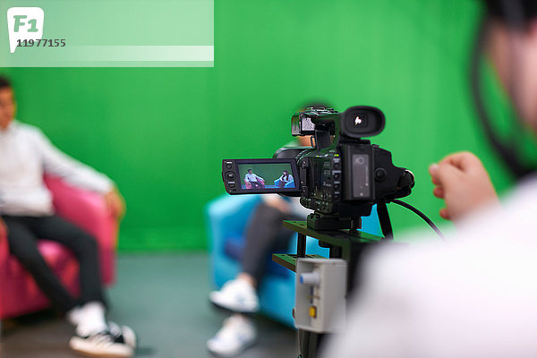 Junge männliche und weibliche Studenten üben im Fernsehstudio mit Green Screen