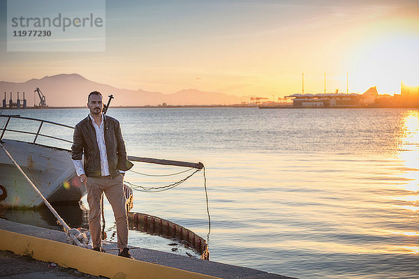 Mann steht bei Sonnenuntergang am Boot und schaut in die Kamera  Cagliari  Sardinien  Italien  Europa