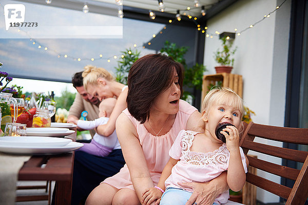 Reife Frau mit Kleinkind-Enkelin isst Brownie beim Familienessen auf der Terrasse