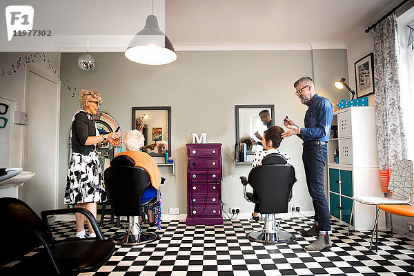 Pärchen in Vintage-Kleidung arbeitet an Kunden in einem skurrilen Friseursalon