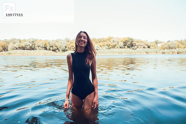 Porträt einer Frau im Badeanzug  die im Wasser steht und lächelnd in die Kamera schaut