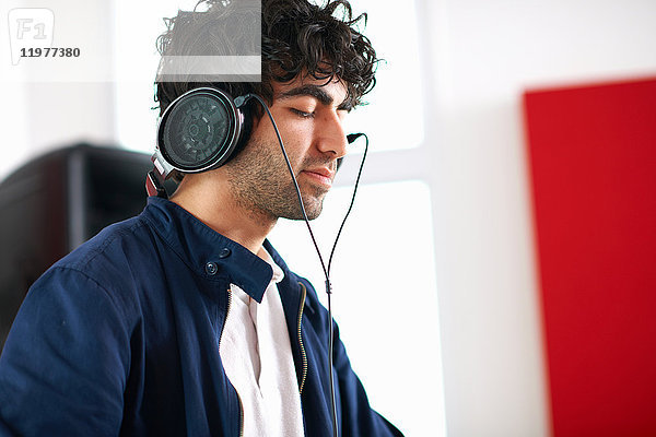 Junger männlicher College-DJ-Student hört Musik über Kopfhörer