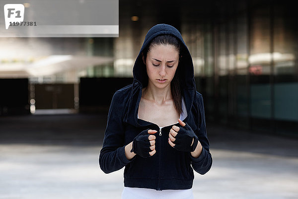 Junge Frau im Freien  mit Kapuzenoberteil und fingerlosen Handschuhen