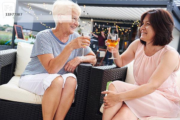 Ältere und reifere Frauen stoßen beim Familienessen auf der Terrasse auf den Wein an