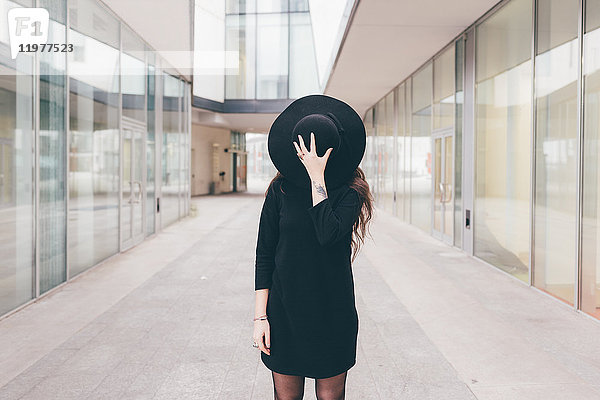 Porträt einer jungen Frau in städtischer Umgebung  Gesicht mit Hut bedeckt
