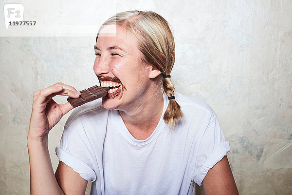 Frau isst eine Tafel Schokolade  Schokolade um den Mund  lacht