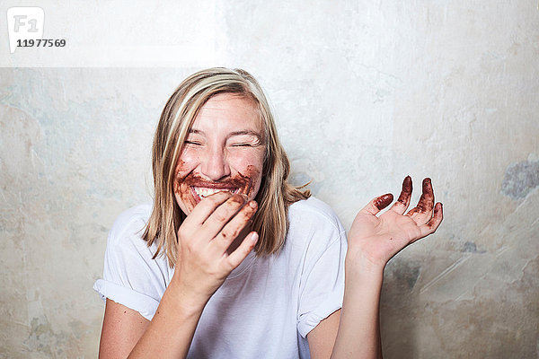 Bildnis einer Frau mit Schokolade an den Händen und um den Mund  lachend