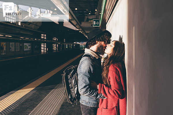 Junges Paar steht auf dem Bahnsteig und küsst sich