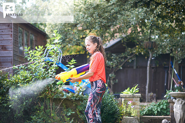 Teenager-Mädchen spritzt Wasserpistole im Garten