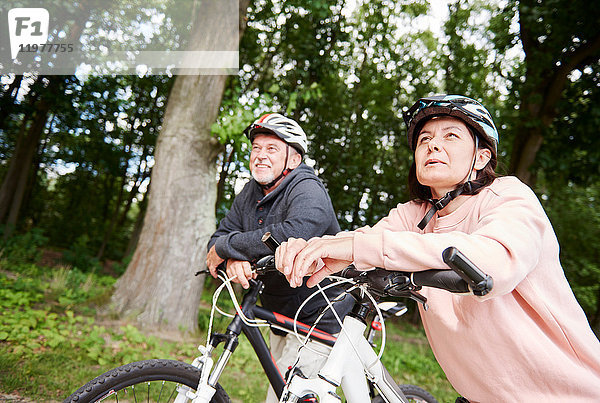 Ein erwachsenes Paar  das mit Fahrrädern den ländlichen Weg entlang fährt und die Aussicht betrachtet