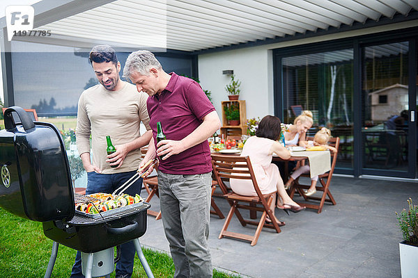 Reife und mittel-erwachsene Männer grillen beim Familienmittagessen auf der Terrasse