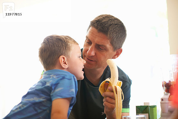 Junge und Vater teilen sich frische Bananen in der Küche