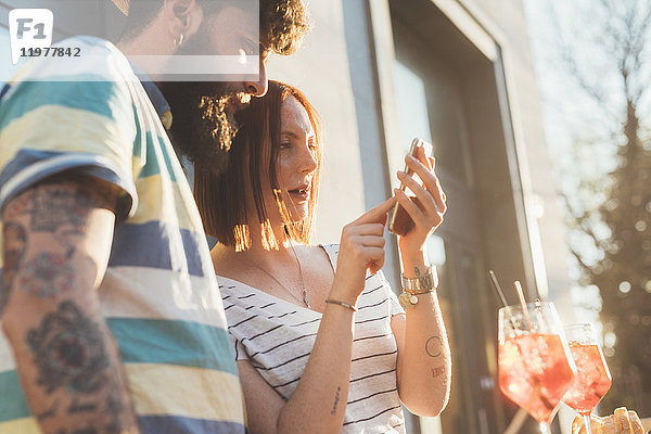 Paar benutzt Touchscreen eines Smartphones im Straßencafé