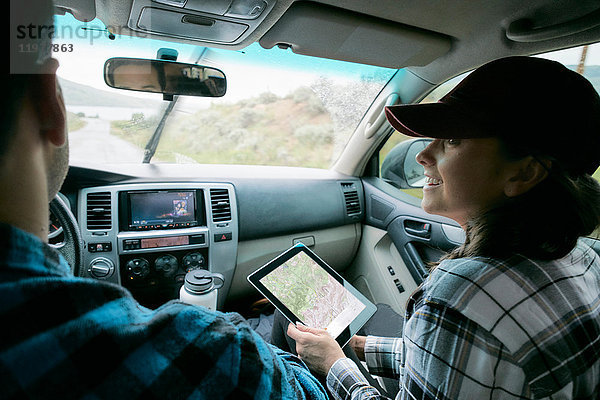 Ehepaar im Auto  Frau hält digitales Tablett mit Karte in der Hand