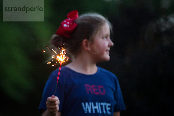 Mädchen schaut weg  während sie nachts am Unabhängigkeitstag eine Wunderkerze hält  USA