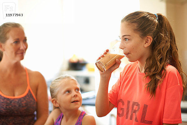Teenager-Mädchen trinkt ein Glas frischen Smoothie in der Küche