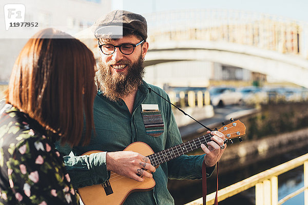 Hipster-Paar spielt Ukulele am Kanal