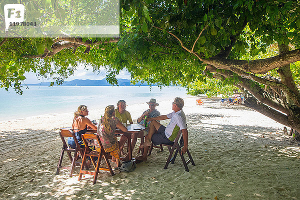 Freunde entspannen sich am Esstisch am Strand  Koh Rang Yai  Thailand  Asien
