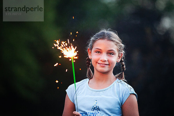 Porträt eines Mädchens mit Wunderkerze im Garten in der Abenddämmerung am Unabhängigkeitstag  USA