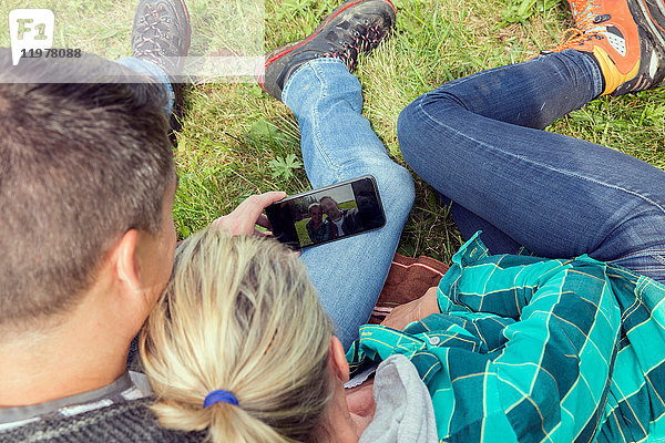 Schrägaufnahme eines Paares  das auf Gras sitzt und Selbsthilfe nimmt