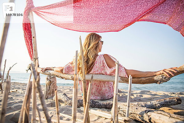 Rückansicht einer Frau  die entspannt am Strand sitzt  Palma de Mallorca  Balearen  Spanien  Europa