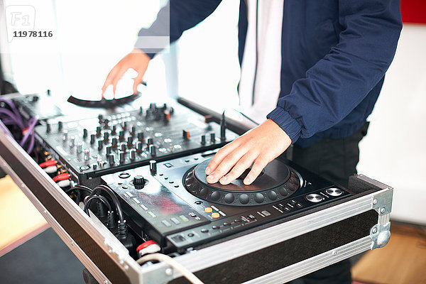 Junger männlicher College-Student dreht DJ-Plattenspieler im Aufnahmestudio