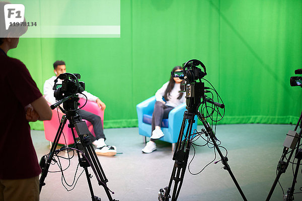 Junge männliche und weibliche Studenten üben im Fernsehstudio mit Green Screen