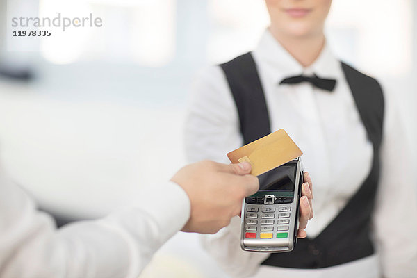 Kellnerin hält Zahlungsautomat in Richtung Kunde  Kunde bezahlt kontaktlos
