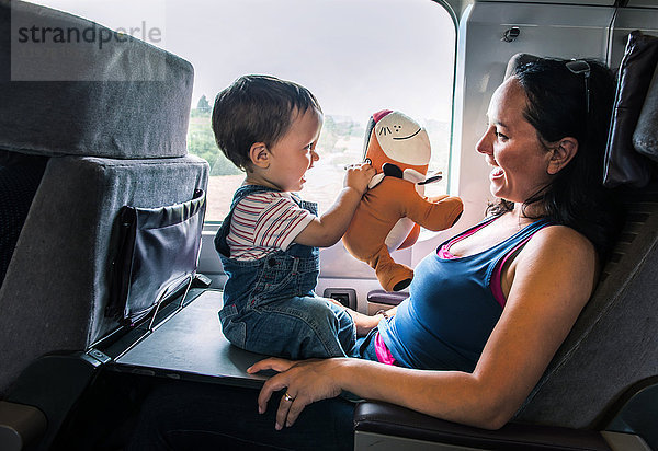 Mutter und kleiner Sohn reisen im Zug und spielen zusammen