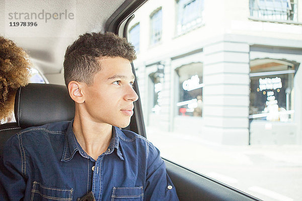 Junger Mann auf dem Beifahrersitz eines Autos  der aus dem Fenster schaut