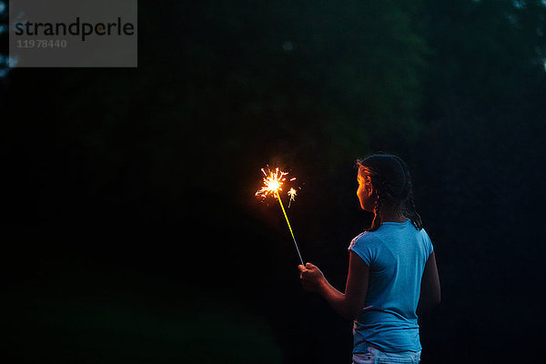 Mädchen starrt nachts am Unabhängigkeitstag auf Wunderkerze im Garten  USA