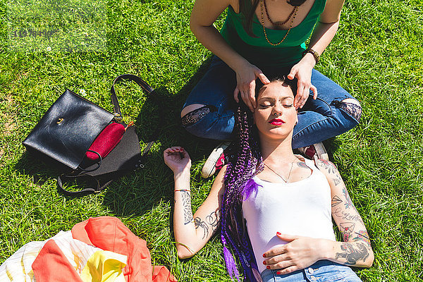 Frau gibt Freundin Kopfmassage auf Gras