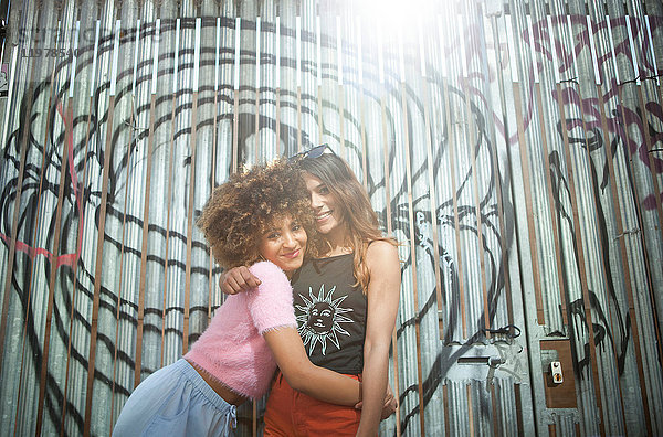 Porträt von zwei jungen Frauen  in städtischer Umgebung  die sich umarmen