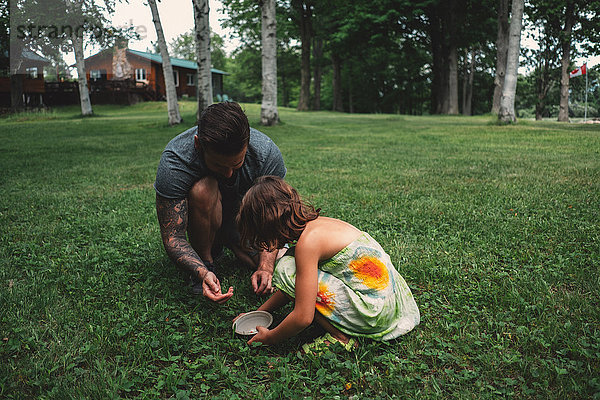 Vater und Tochter im Freien  in der Hocke  Beeren sammeln