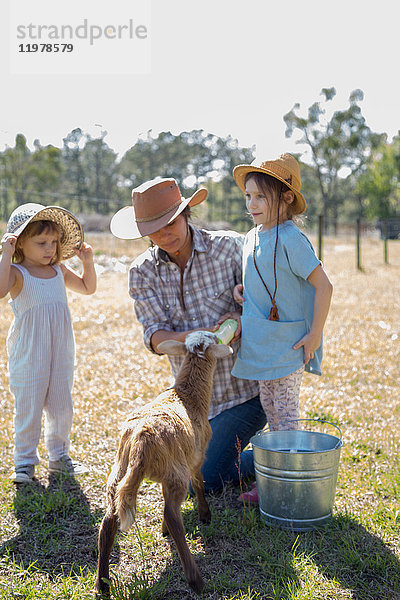 Mutter und zwei Kinder auf dem Bauernhof  Flaschenfütterung junger Ziegen