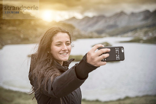 Teenager  der lächelnd vor dem See Selfie nimmt  San Bernardino  Tessin  Schweiz  Europa